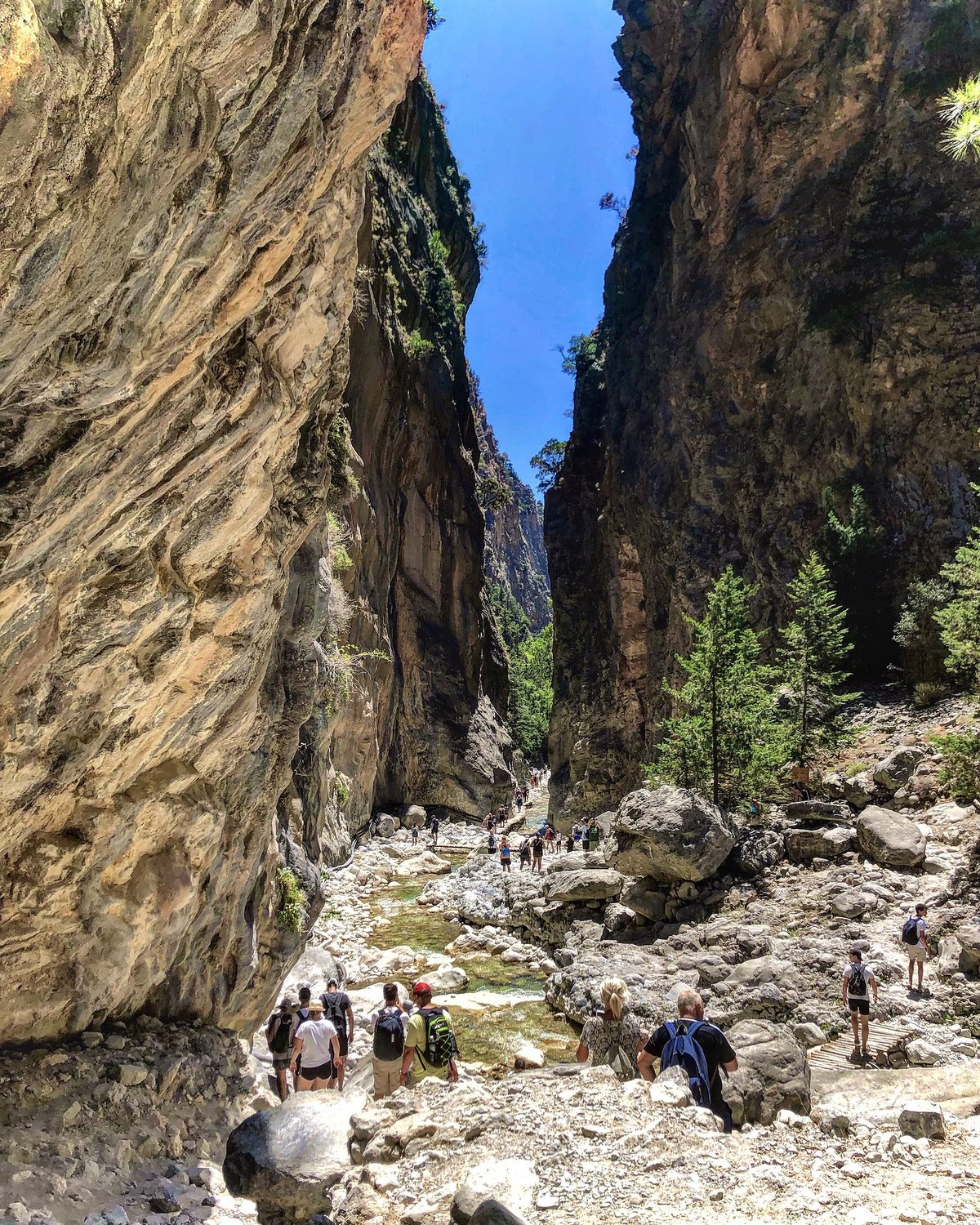 Hikers walking between the high canyon walls of the Samaria Gorge, Crete